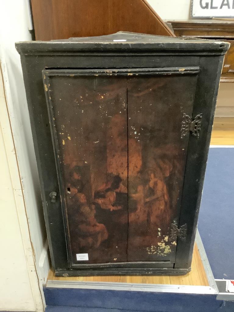 A late 18th century East Anglian lacquered hanging corner cupboard, painted with an interior scene with figures, width 51cm, depth 22cm, height 82cm